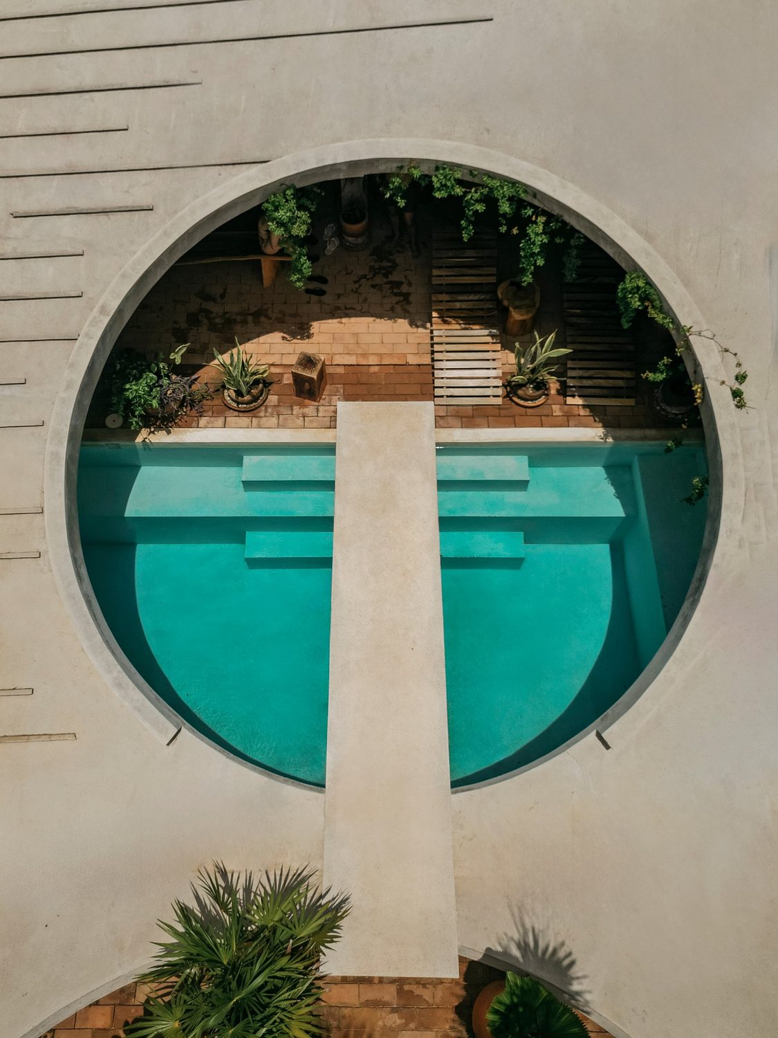 Casa Hezbo from above: the round opening, the turquoise pool and the concrete bridge