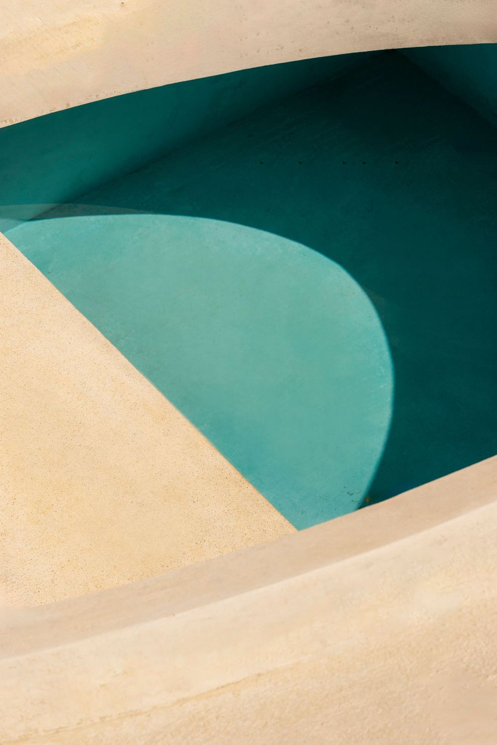 The curve of the turquoise pool against smooth concrete