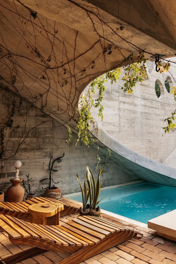Wooden lounger beside the pool under the curved concrete wall