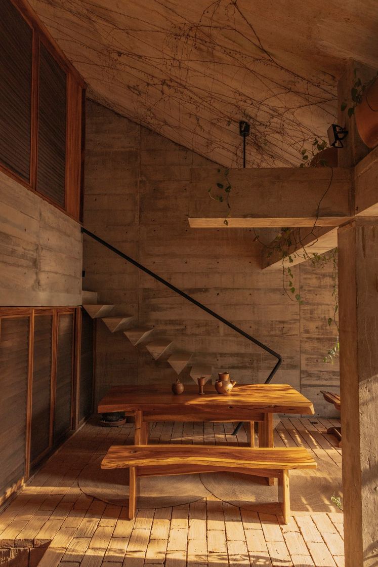 Wooden dining table under the floating concrete staircase
