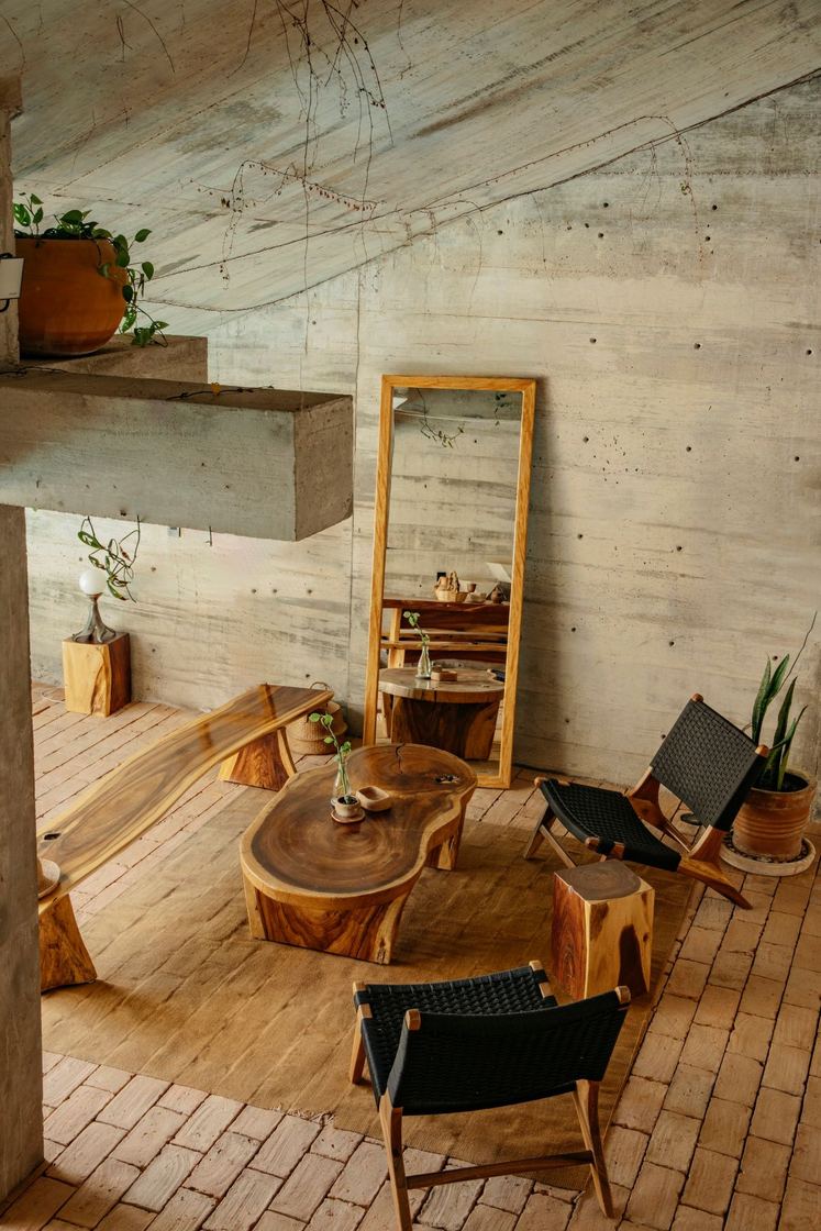 Living area with a carved wooden table, leather chairs and a tall mirror